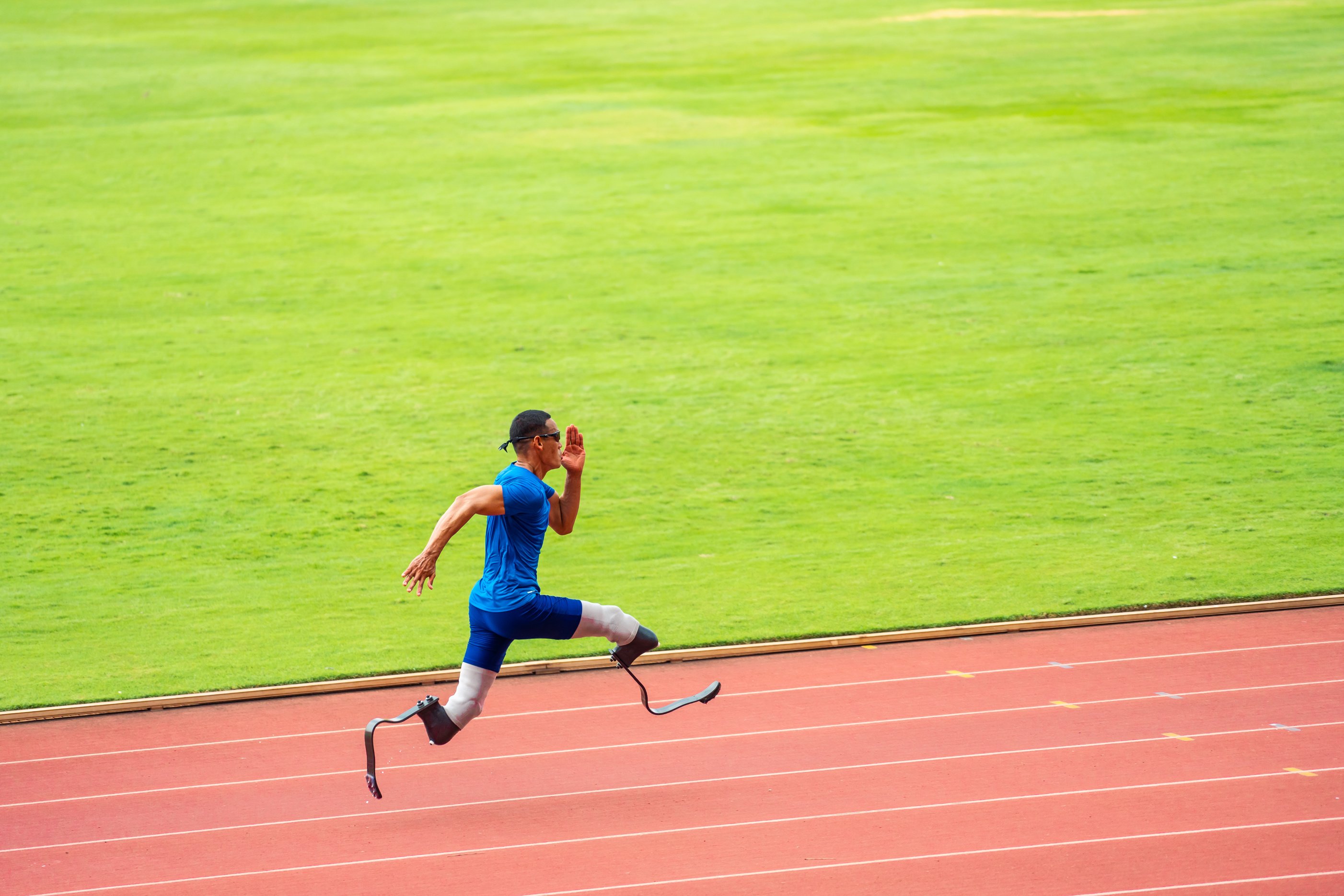 Asian para-athletes disabled with prosthetic blades running at stadium. Attractive amputee male runner exercise and practicing workout for Paralympics competition regardless of physical limitations.